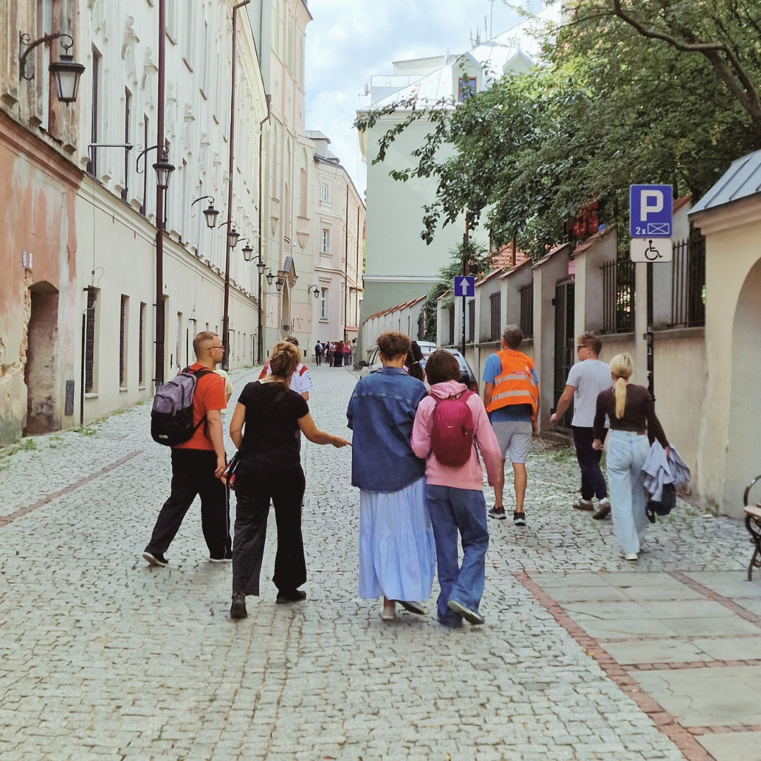 Grupa osób spacerująca wspólnie po zabytkowej ulicy.